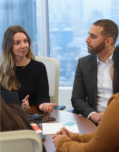 Three people from the OHA and Proximity Institute discuss around a table.